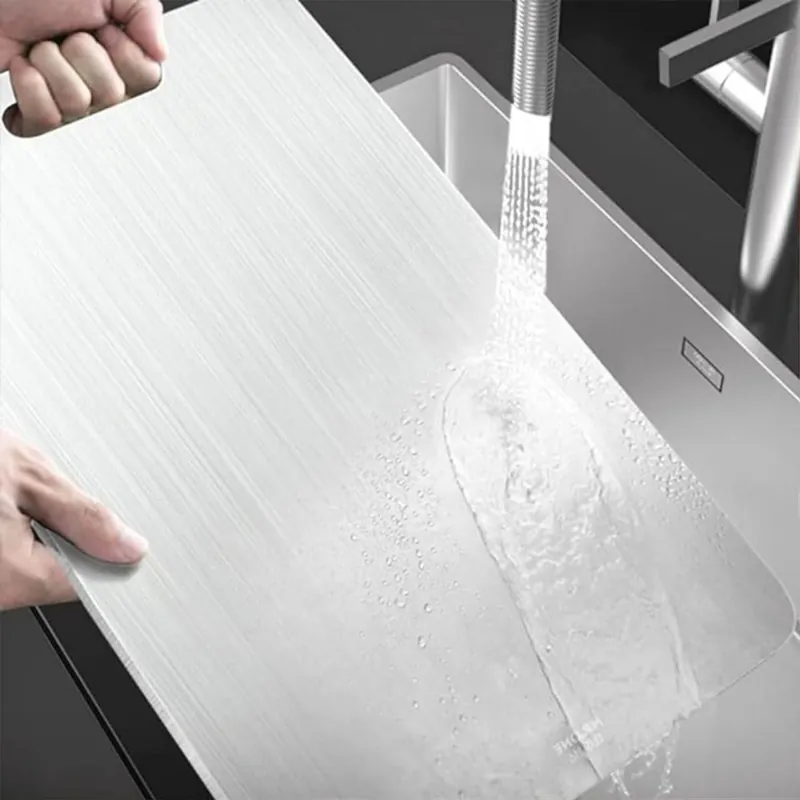 The titanium board held under a running kitchen tap